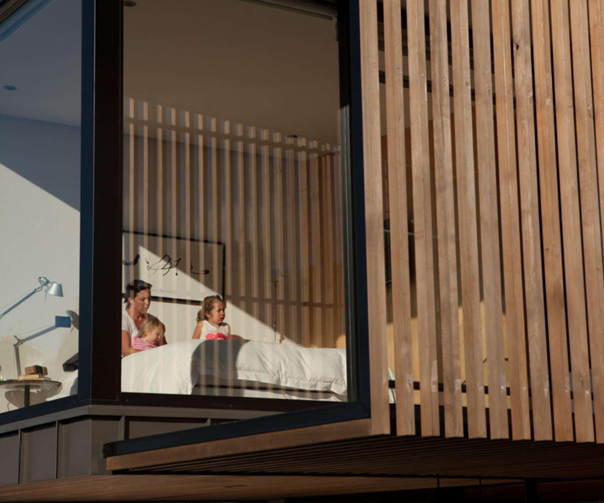 The bedrooms and bathrooms are all upstairs. Although it is small, the main bedroom feels larger because of its expansive windows. Cedar slats provide shade from the late-afternoon summer sun. 