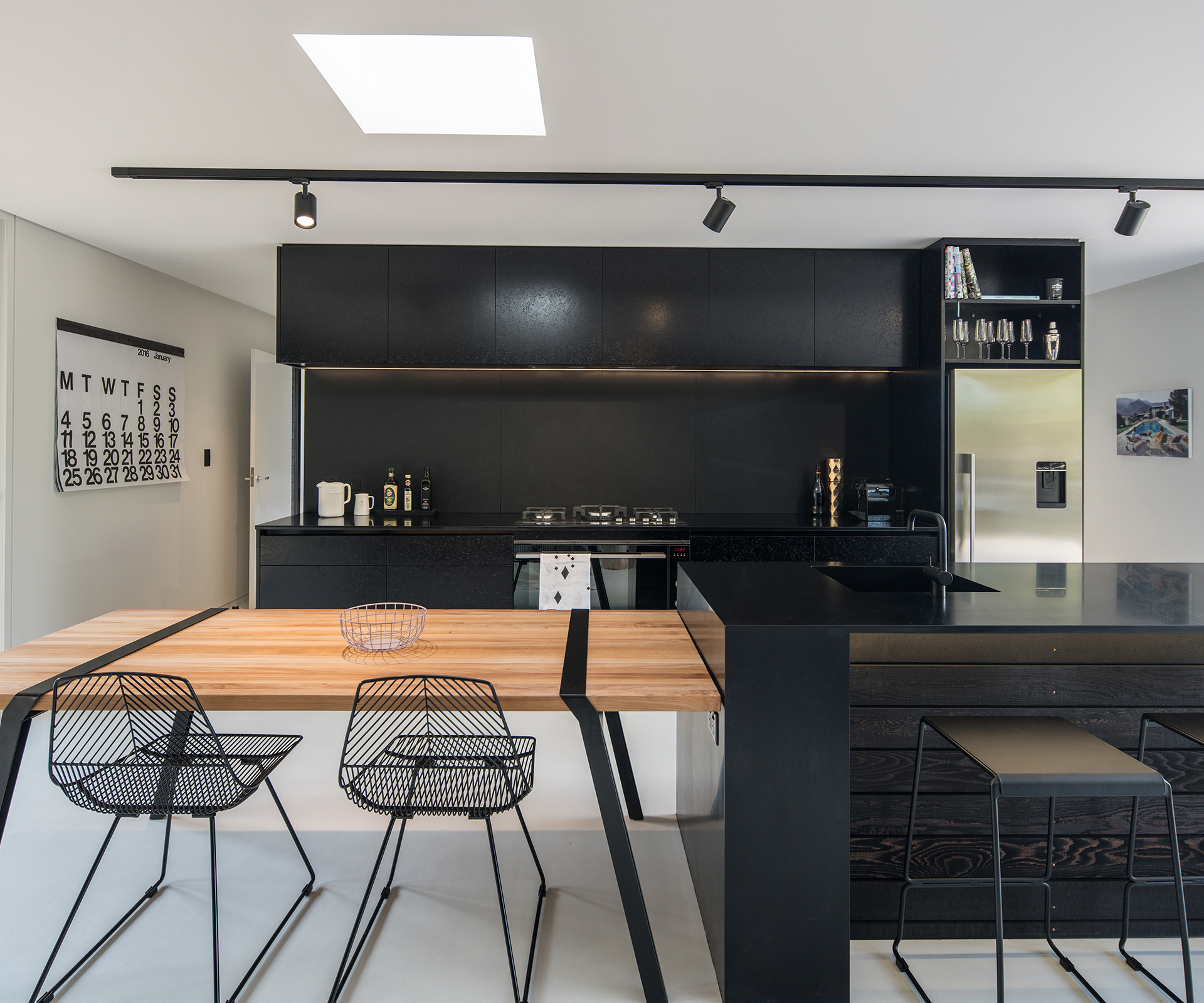 The black-and-white kitchen also features a movable table adjacent to the island. Photograph by Jeremy Toth. 