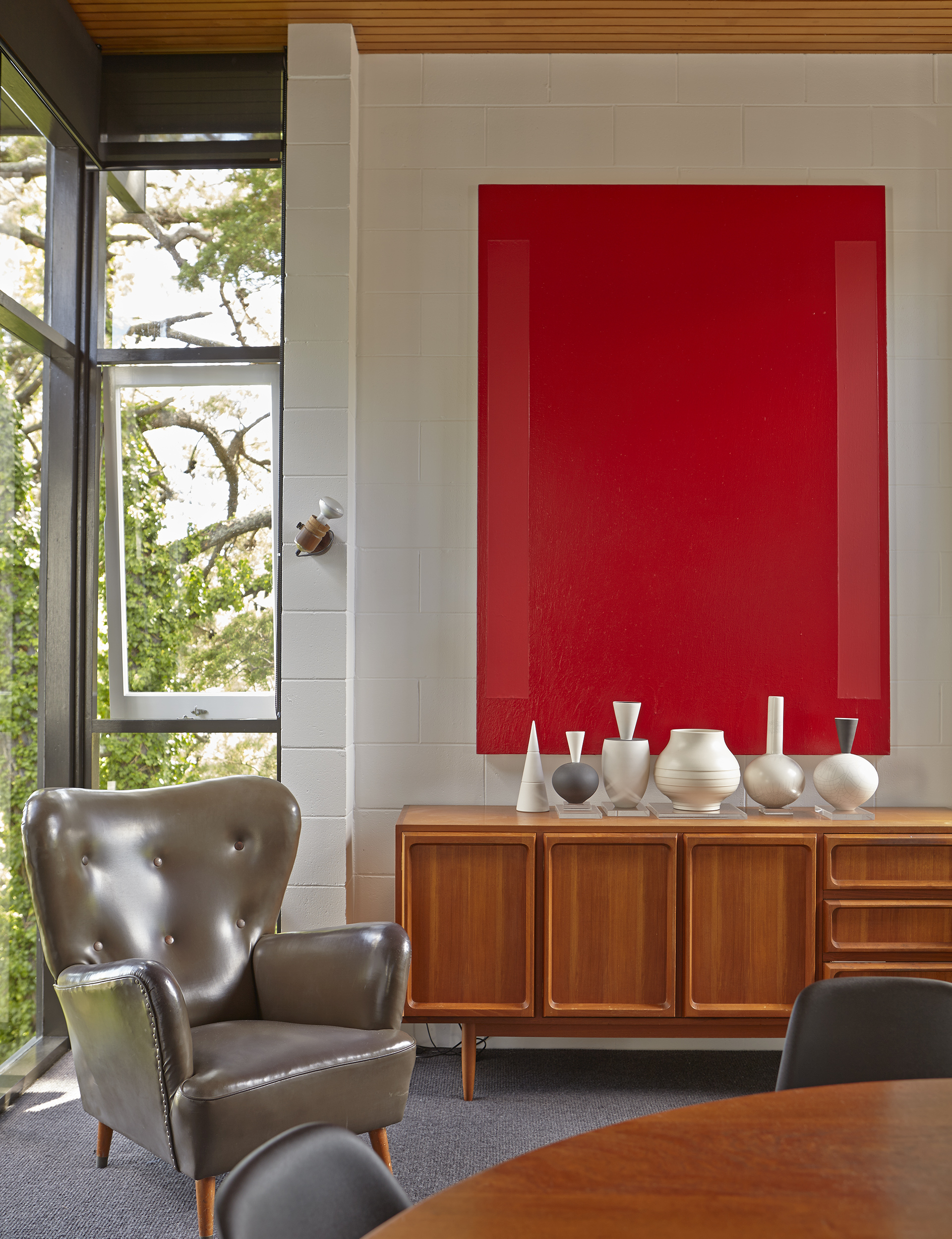 Max Gimblett’s ‘Crimson / Red’ hangs over a mid-century buffet by Parker Furniture, with vases by Peter Collis, John Parker and Keith Murray. Dean and Bentley bought the Australian mid-century wingback armchairs in their original vinyl from Bondi markets in Sydney.