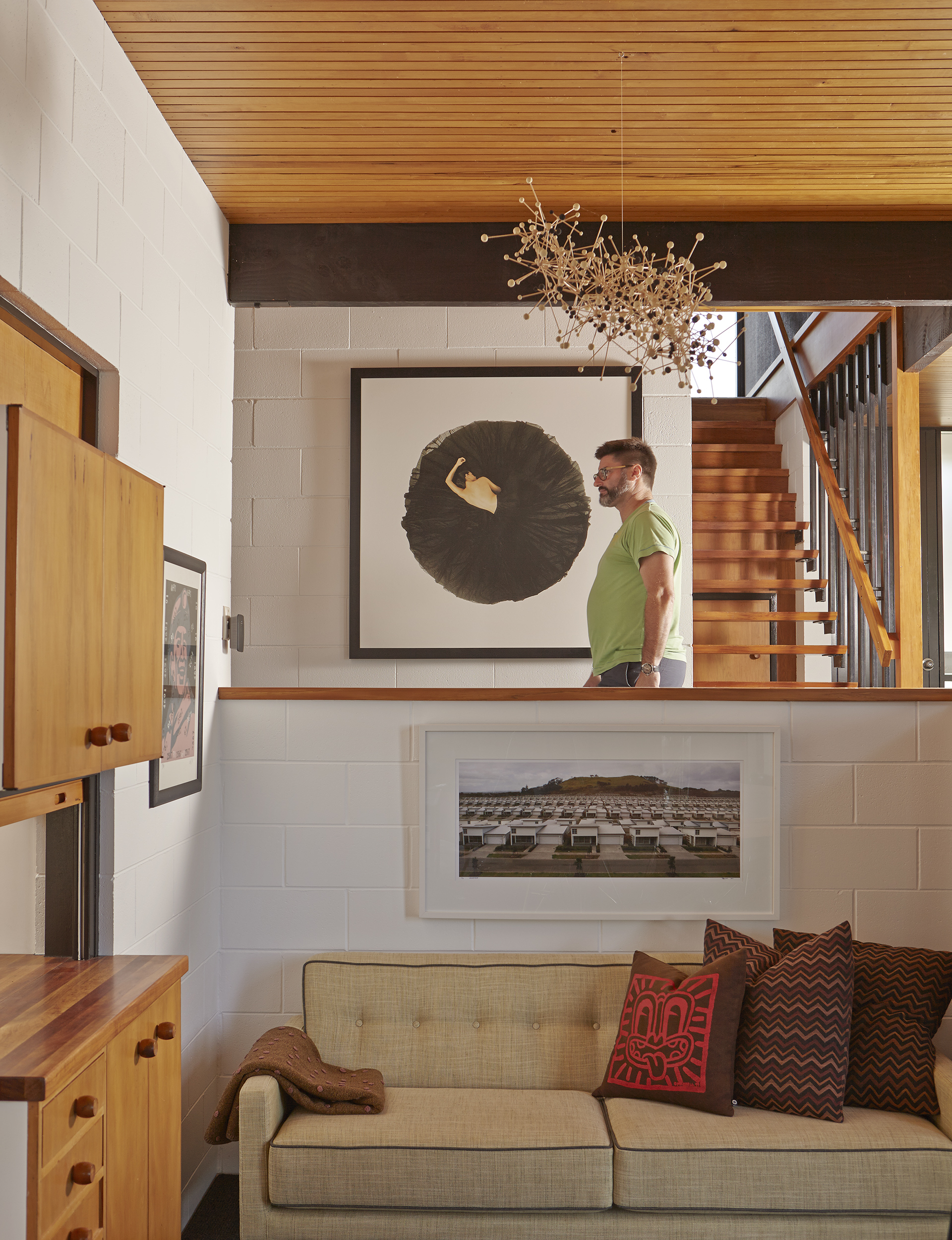 Dean walks past a photograph entitled ‘Circle’ by Rohan D Souza, while above him is Constellation’, a mounted sculpture by Kevin Osmond, a bespoke piece created for the home while the artist was in residence. The art work on the lower wall is ‘Stonefields’, an image by P J Paterson.