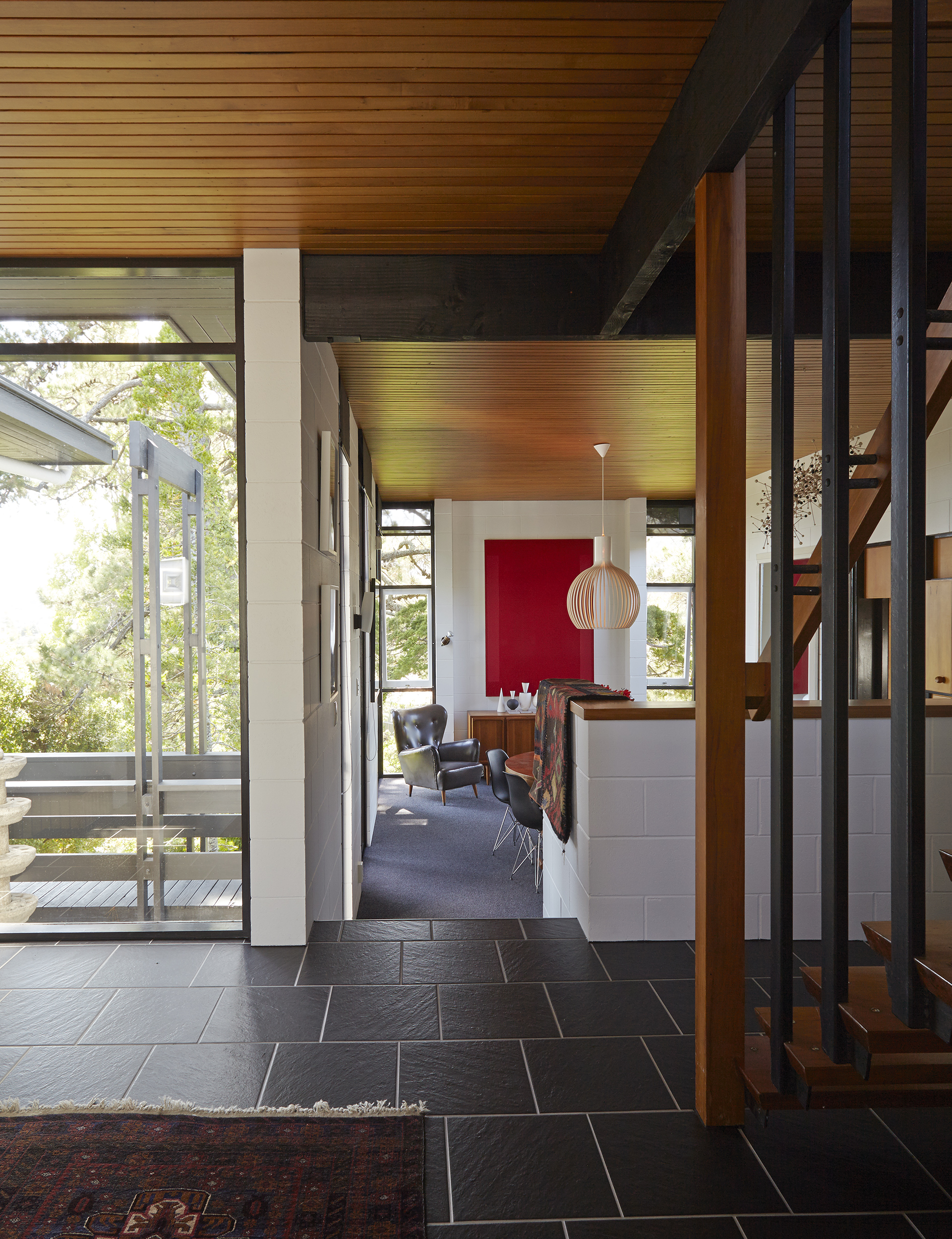 The entrance reveals the home’s original tawa ceiling. Beyond hangs an ‘Octo’ pendant light by Seppo Koho for Secto Design, and ‘Crimson/Red’, a work by Max Gimblett. 