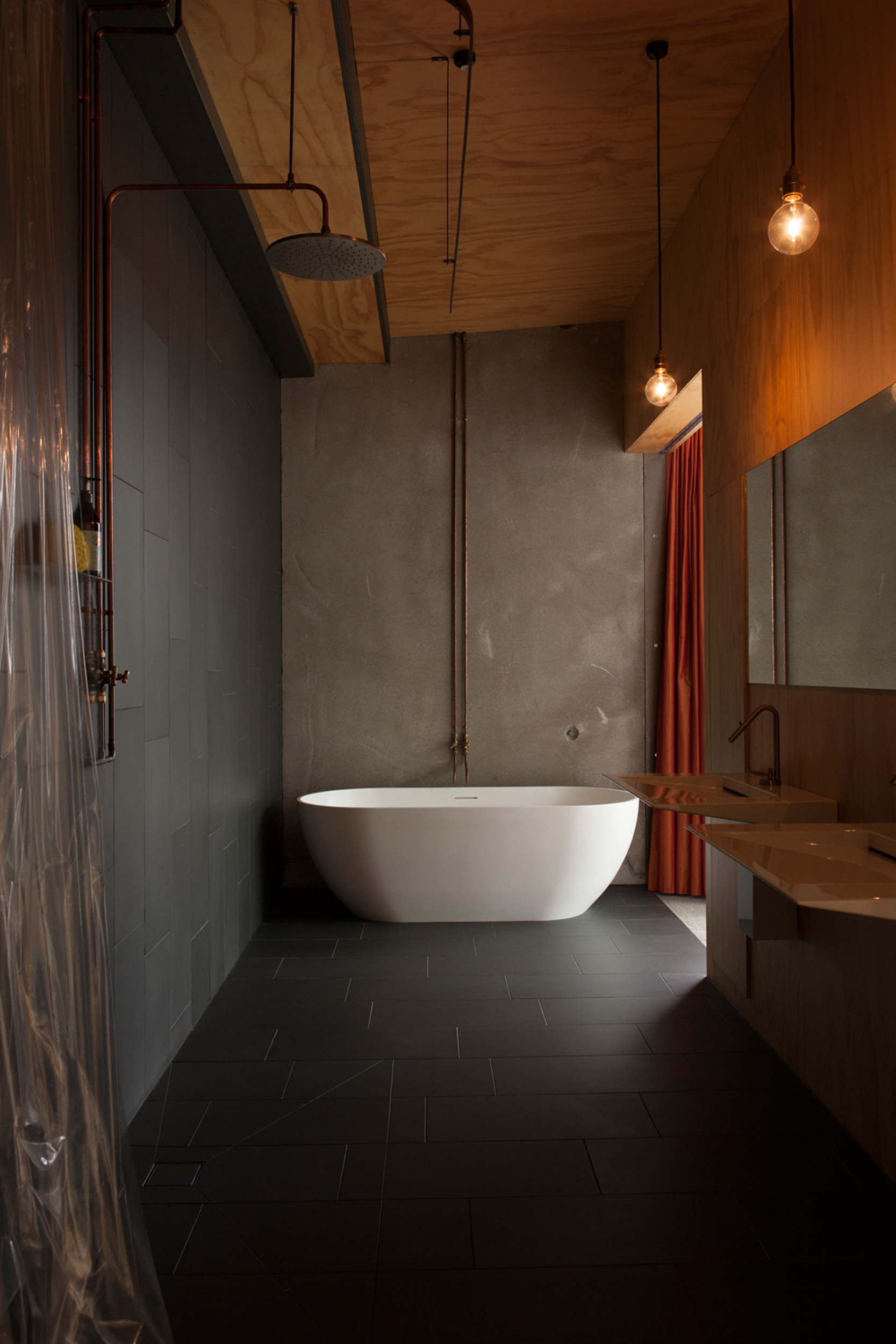 The ensuite bathroom has a deliberately raw finish with exposed pipes. 